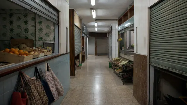 Pasillo de un mercado tradicional con puestos cerrados y frutas en una vitrina