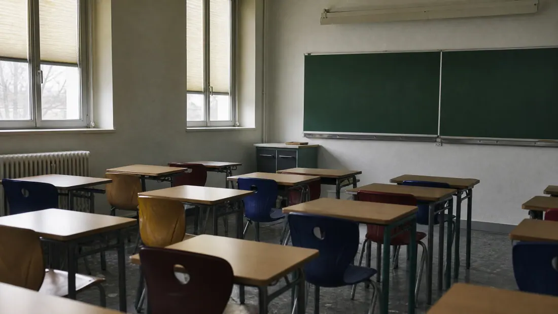 Aula escolar con pupitres individuales y pizarra verde al fondo