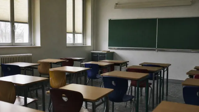 Aula escolar con pupitres individuales y pizarra verde al fondo