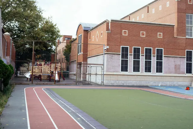 Pista de atletismo y patio de un colegio junto a un edificio de ladrillo