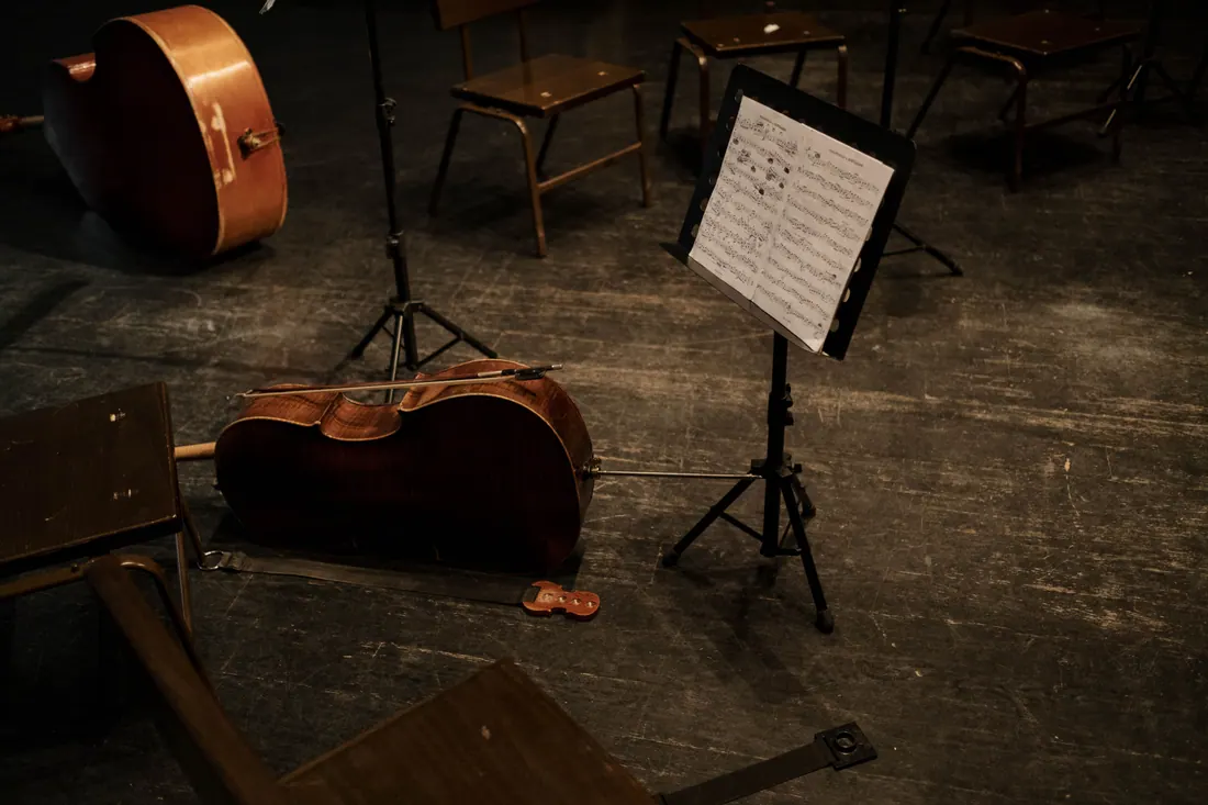 Instrumentos de cuerda y un atril con partitura sobre un escenario vacío