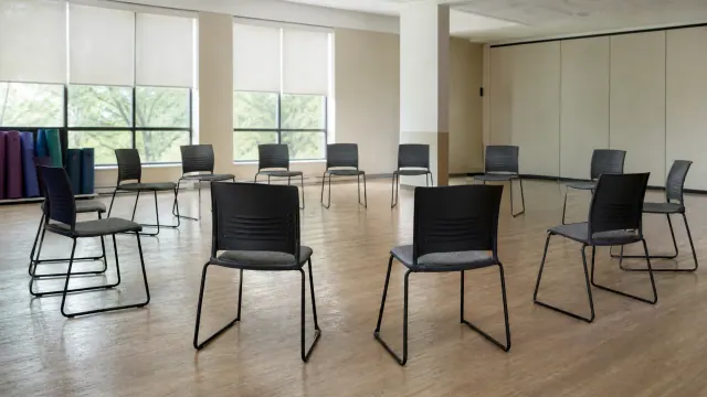 Sala de reuniones o aula con sillas negras de metal distribuidas en círculo