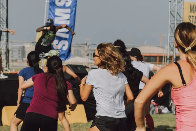 Grupo de personas haciendo ejercicio al aire libre junto a un escenario