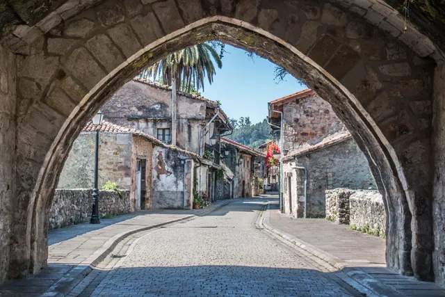 Arco de piedra enmarca una calle empedrada de un pueblo