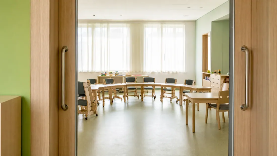Sala de reuniones con mesas de madera dispuestas en semicírculo y sillas alrededor