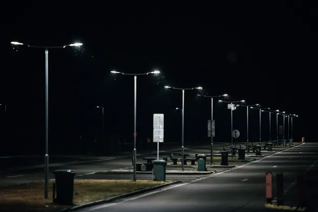 Farolas encendidas de noche a lo largo de una calle vacía