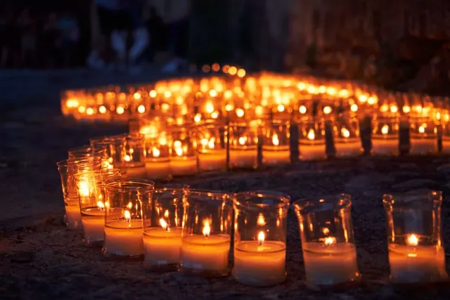 Celebración festiva nocturna en pueblo español con iluminación tradicional y vecinos reunidos