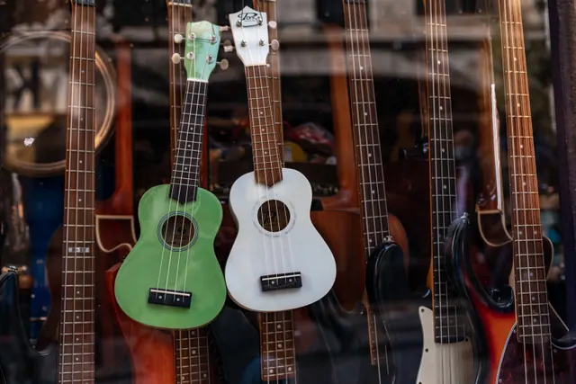Ukeleles y guitarras colgados en el escaparate de una tienda de música