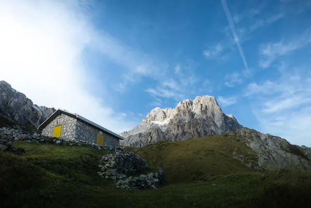 Comida caliente servida en refugio de montaña con vistas a cumbres nevadas