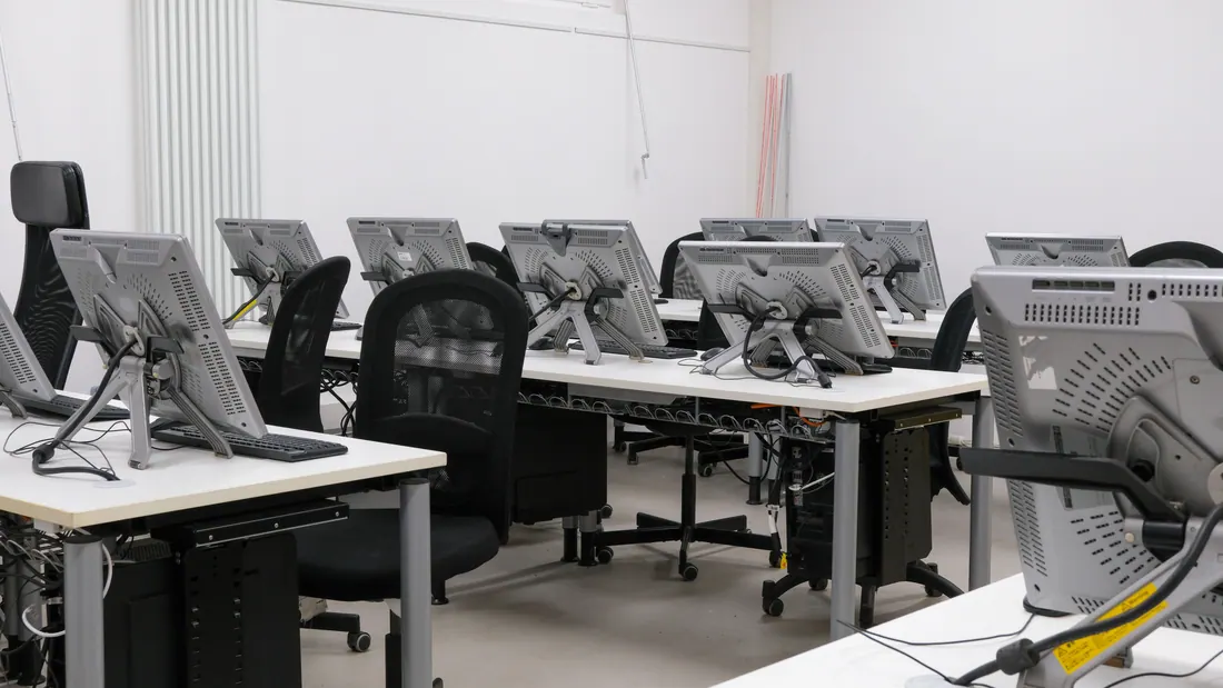 Aula informática vacía con varios monitores y sillas de oficina