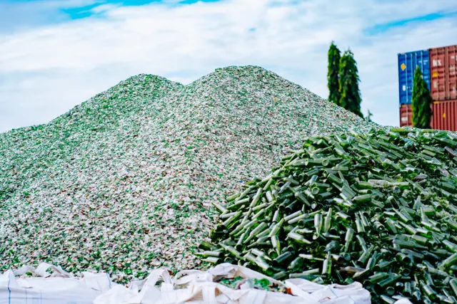 Montañas de vidrio triturado y botellas en una planta de reciclaje