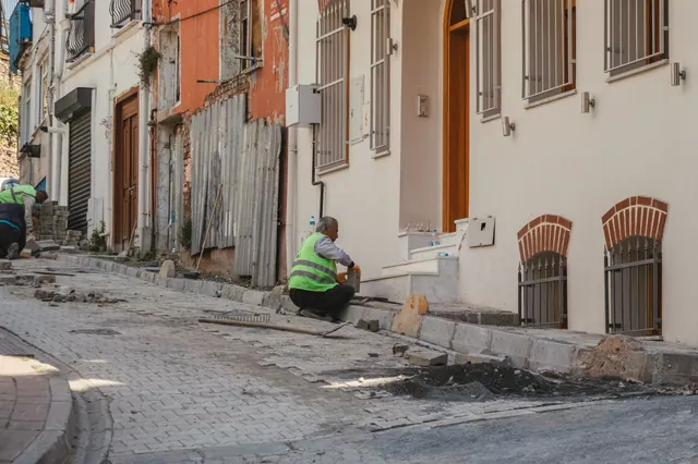 Acera en obras con adoquines levantados y un alcorque con árbol