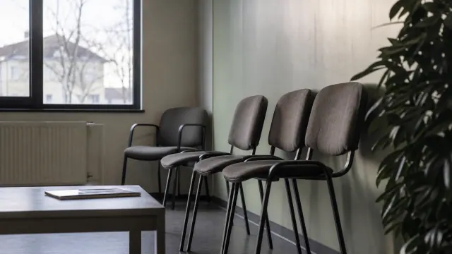 Sillas grises de espera en una sala de oficina junto a una ventana