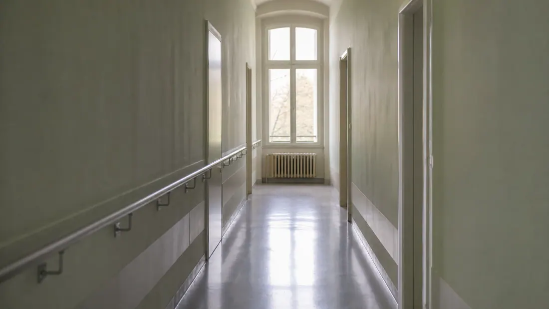 Pasillo de hospital o clínica con pasamanos metálicos y puertas a los lados