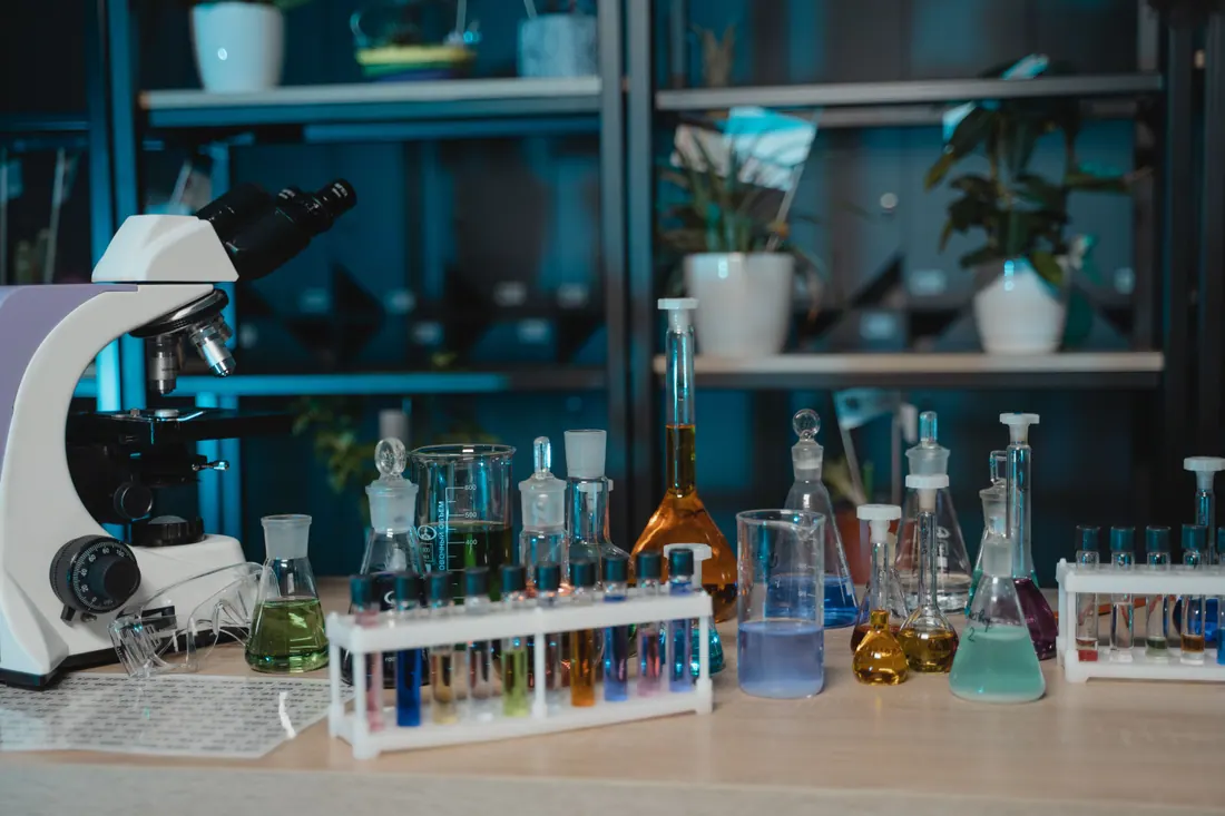 Microscopio y material de laboratorio con tubos y matraces de colores