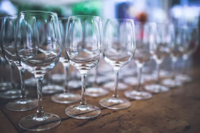 Copas de vino vacías alineadas sobre una mesa de madera