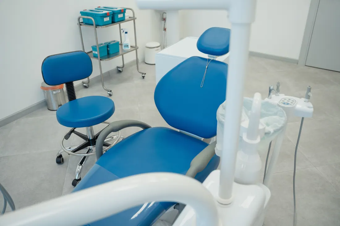 Consulta dental vacía con sillón y taburete azules
