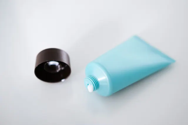 Un tubo de cosmético sin etiquetar con su tapón sobre una mesa