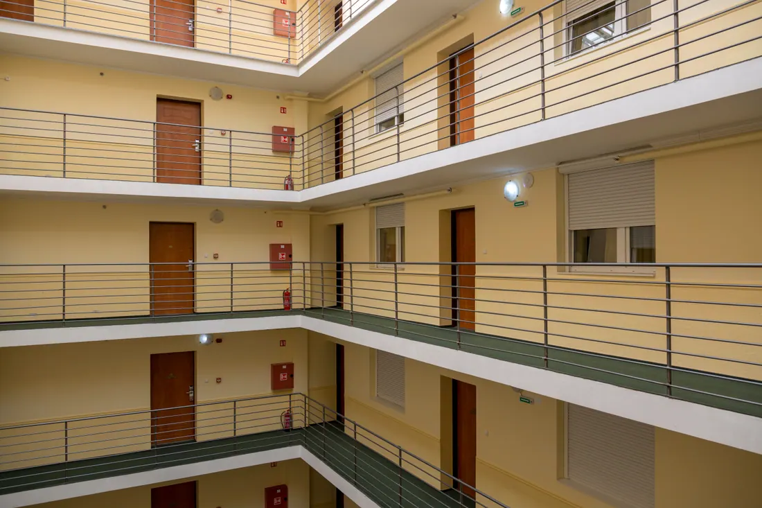 Interior de un edificio con varios pisos de pasillos y puertas