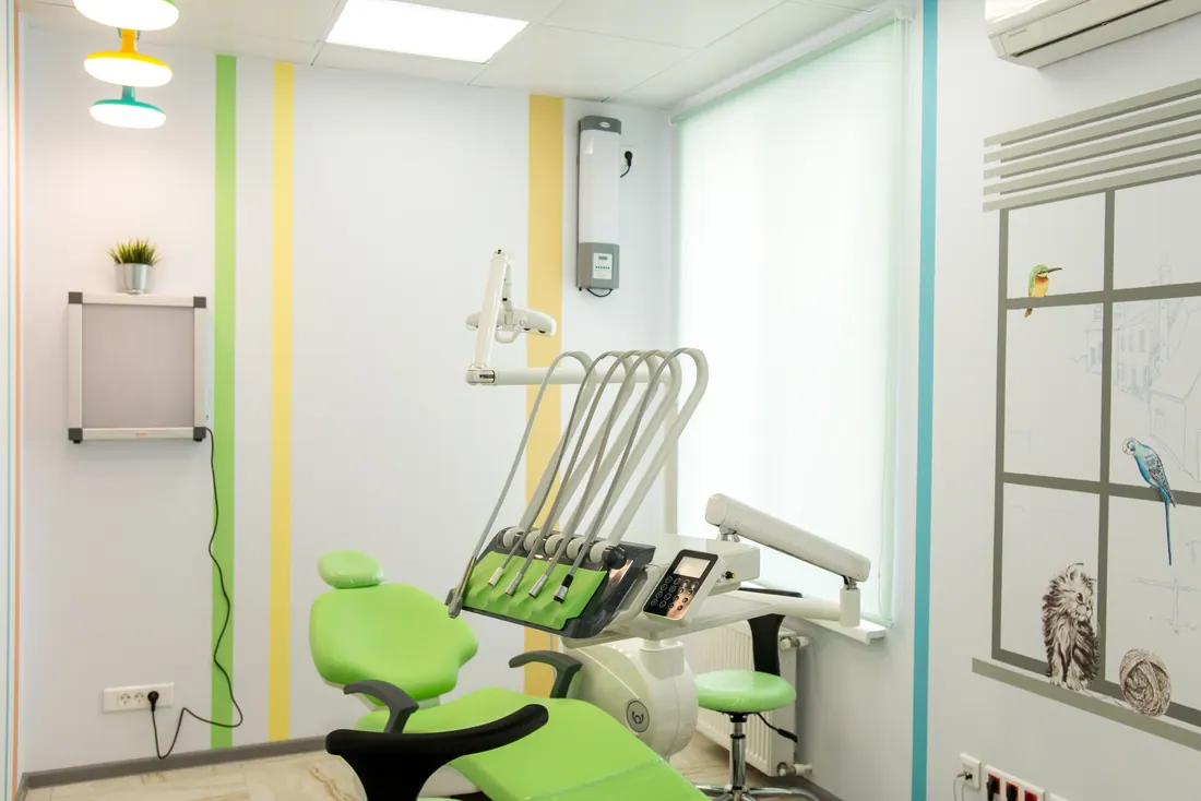 Consulta dental infantil con sillón verde y decoración de animales