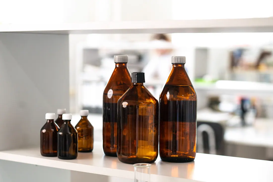 Varios frascos de vidrio ámbar sobre una estantería en un laboratorio