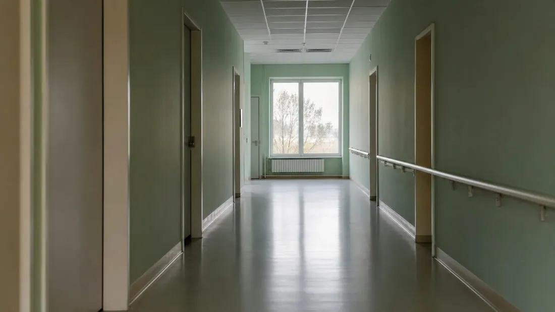 Pasillo de centro sanitario con paredes verdes y suelo de linóleo brillante
