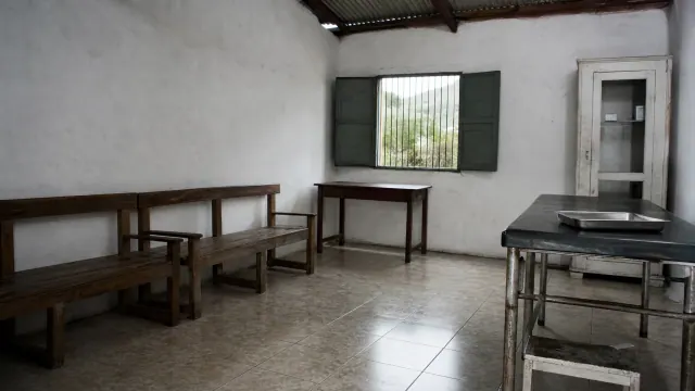 Sala diáfana con bancos de madera, escritorios y pizarra verde junto a ventana