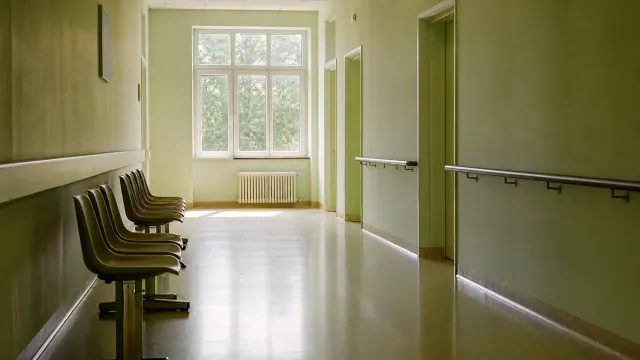 Pasillo de centro sanitario con sillas de espera junto a una ventana