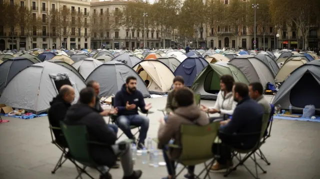 Un grupo de personas acampadas en una plaza urbana rodeadas de tiendas de campaña