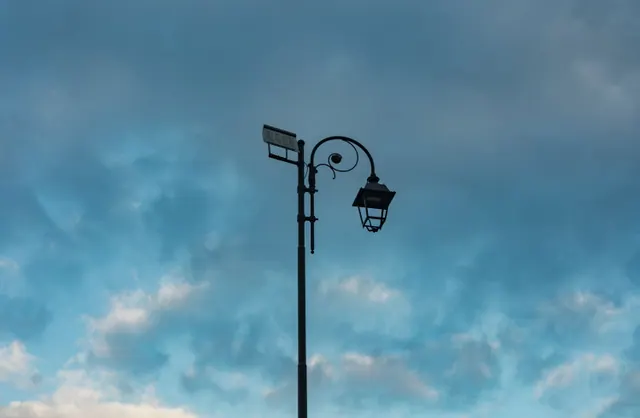 Farola con panel solar recortada contra un cielo nuboso