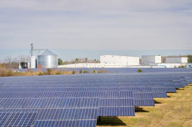 Planta solar con paneles fotovoltaicos junto a silos industriales