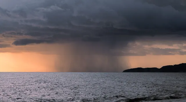 Tormenta descargando lluvia sobre el mar al atardecer