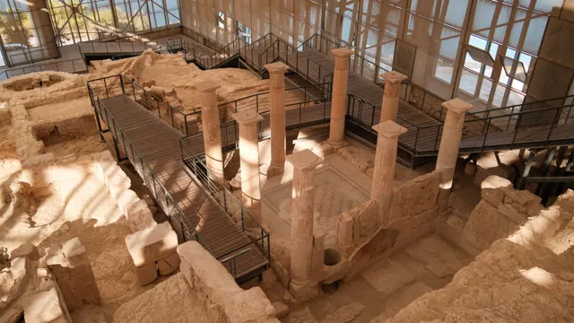 Yacimiento arqueológico romano con columnas cubierto por una estructura moderna