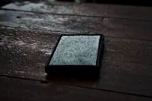 Un teléfono móvil mojado sobre una mesa de madera