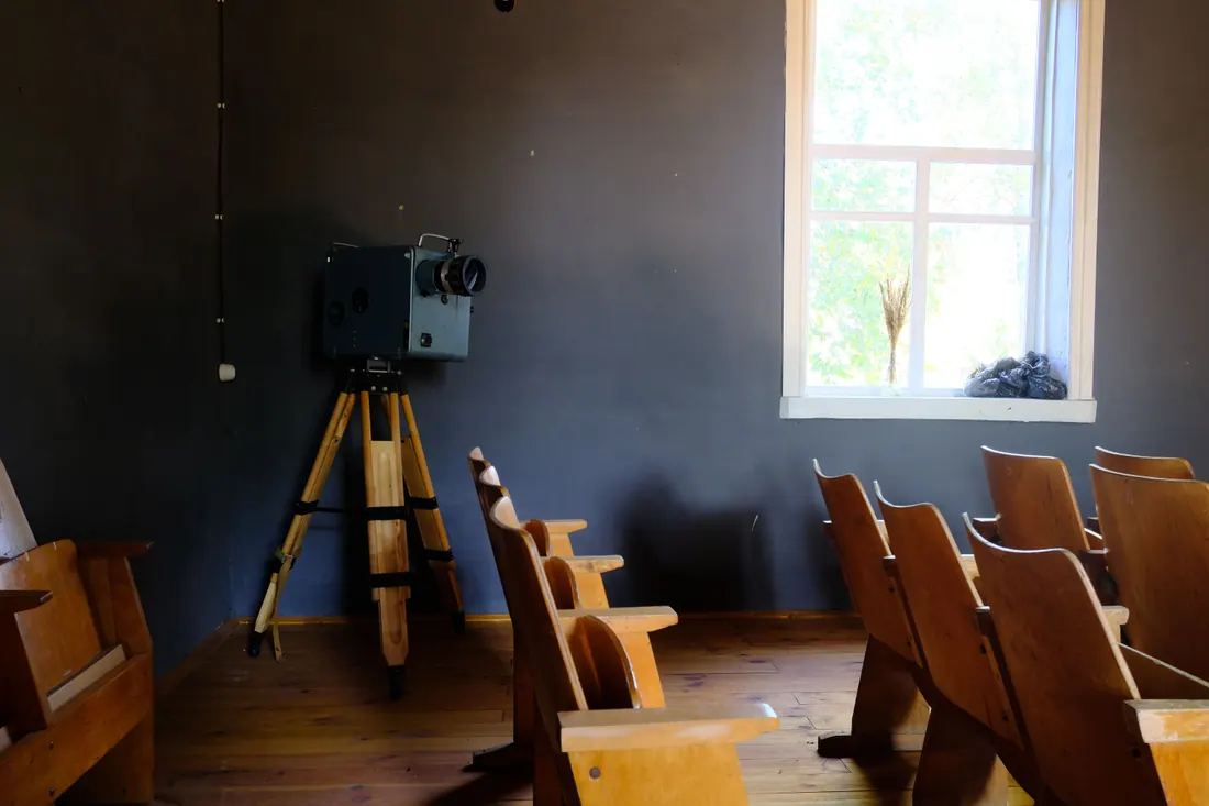Antigua sala de cine con butacas de madera y un proyector