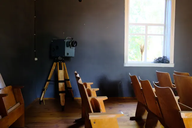 Antigua sala de cine con butacas de madera y un proyector