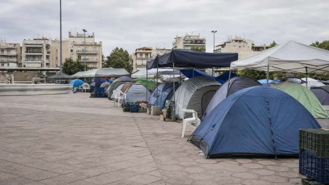 Campamento de tiendas de campaña y estructuras improvisadas en una plaza urbana
