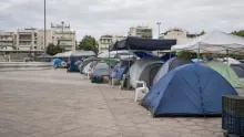 Campamento de tiendas de campaña y estructuras improvisadas en una plaza urbana