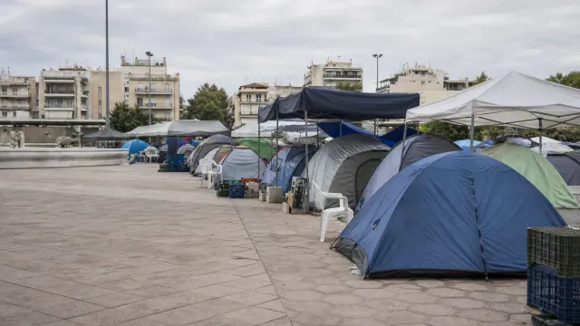 Campamento de tiendas de campaña y estructuras improvisadas en una plaza urbana