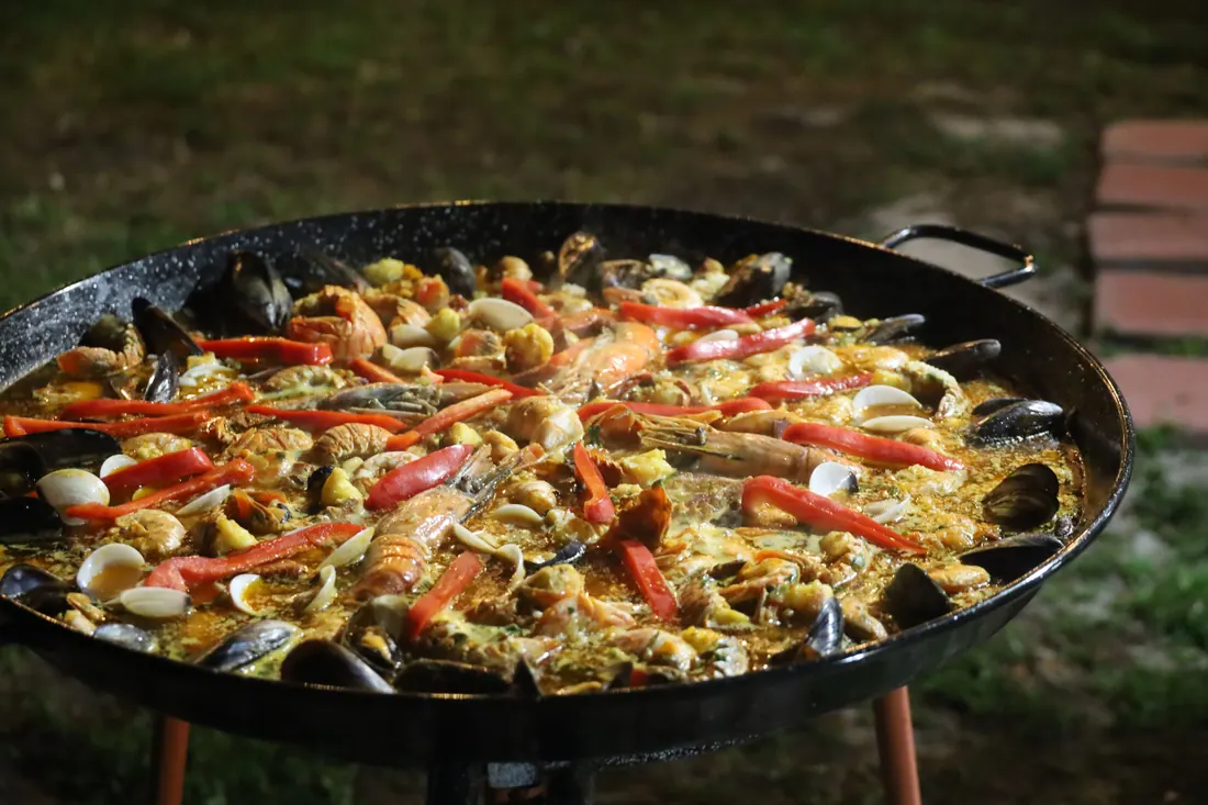 Una paella de marisco cocinándose en una paellera al aire libre