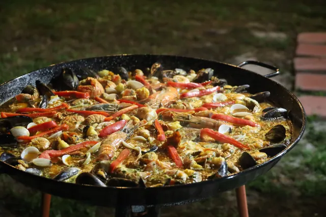 Una paella de marisco cocinándose en una paellera al aire libre