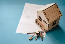 Una casa de madera en miniatura con llaves sobre un documento