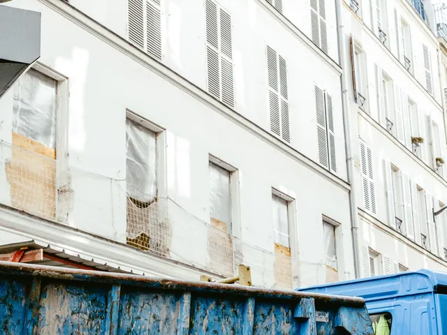 Bajos de un bloque de viviendas en obras, con vallas y andamios en la acera