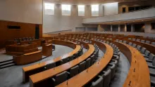 Hemiciclo de un parlamento con bancadas de madera y asientos negros vacío