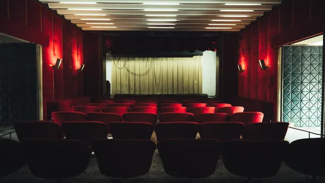 Interior de una sala de cine vacía con butacas rojas