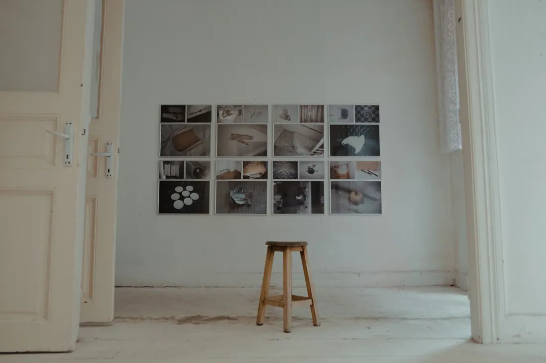 Un taburete de madera frente a una pared con fotografías enmarcadas