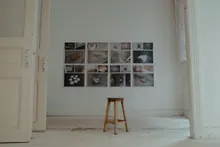 Un taburete de madera frente a una pared con fotografías enmarcadas