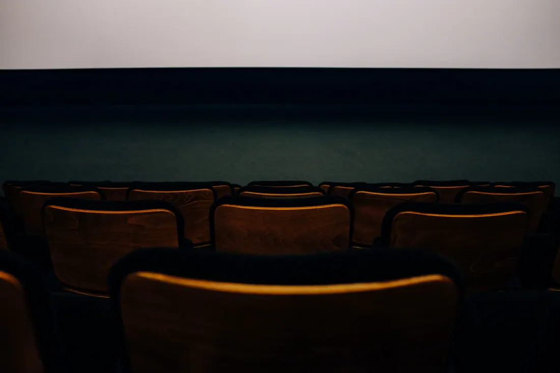 Butacas vacías de madera frente a la pantalla de un cine