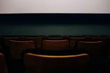 Butacas vacías de madera frente a la pantalla de un cine
