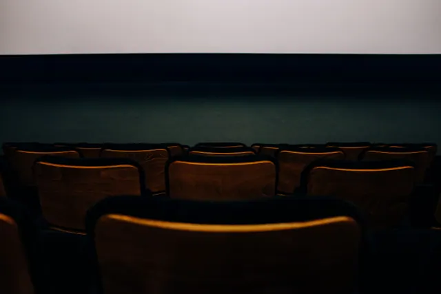 Butacas vacías de madera frente a la pantalla de un cine